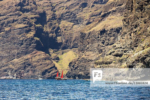Segelboot mit roten Segeln vor der Steilküste bei Los Gigantes  Santiago del Teide  Teneriffa  Kanarische Inseln  Spanien  Europa