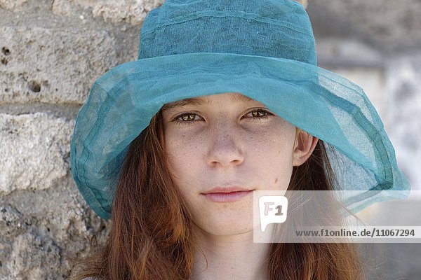 Red-haired girl with a turquoise sun hat looking seriously  portrait  Italy  Europe