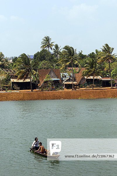 Traditionelle Häuser und Palmen  Boot in einem See in Senmonorom  Sen Monorom  Mondul Kiri  Provinz Mondulkiri  Kambodscha  Asien