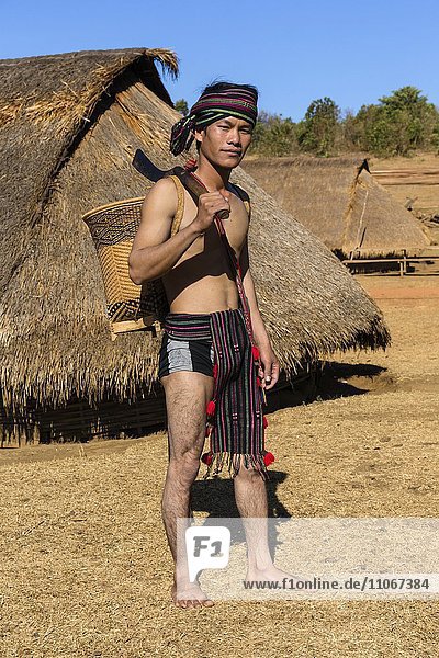 Mann in traditioneller Kleidung vor Phnong Haus  Ethnische Minderheit  Pnong  Bunong  Senmonorom  Sen Monorom  Provinz Mondulkiri  Kambodscha  Asien