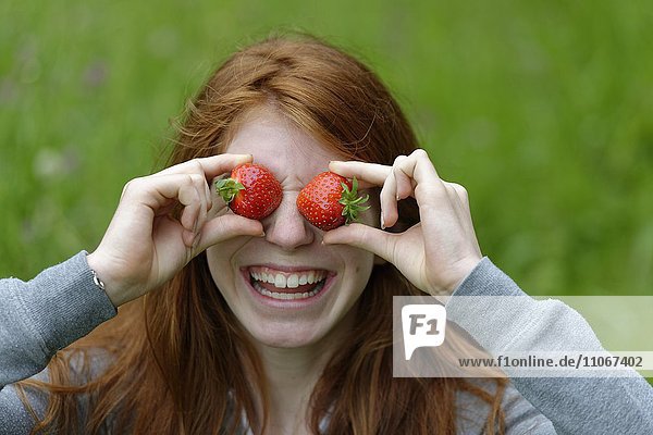 Young girl  female teenager with strawberries in front of the eyes  Bavaria  Germany  Europe