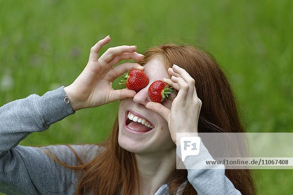 Young girl  female teenager with strawberries in front of the eyes  Bavaria  Germany  Europe