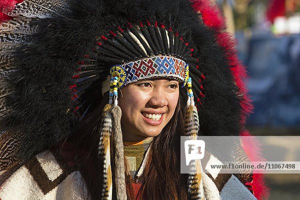 Junge Frau  Asiatin mit Indianerschmuck bei einem Festival mit Kopfschmuck und Federhaube  Chiang Rai Fest  Chiang Rai  Nordthailand  Thailand  Asien