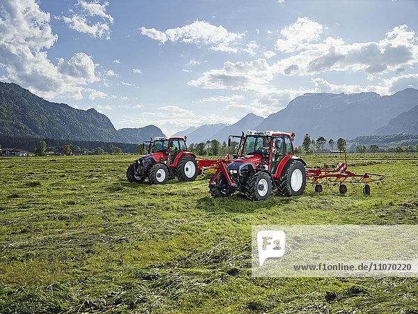 Zwei Traktoren mähen und verteilen das geschnittene Gras mit einem Heuwender  Kundl  Inntal  Tirol  Österreich  Europa