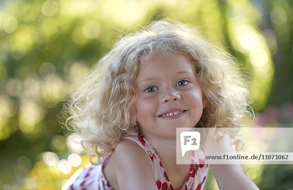 Kleines Mädchen mit blonden Lockenhaaren im Garten  Portrait  Schweden  Europa