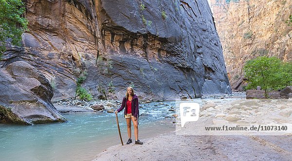Wanderin steht am Fluss  Zion Narrows  Engstelle des Virgin River  Steilwände des Zion Canyon  Zion Nationalpark  Utah  USA  Nordamerika
