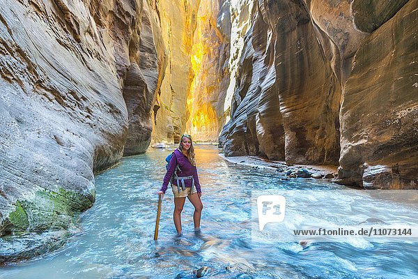 Wanderin steht im Fluss  Zion Narrows  Engstelle des Virgin River  Steilwände des Zion Canyon  Zion Nationalpark  Utah  USA  Nordamerika