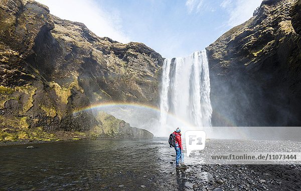 Wanderer vor Wasserfall Skogafoss mit Regenbogen Skogar Süd Island Island Europa