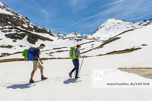 Two hikers walk over snowfield  Rohrmoos-Untertal  Schladming Tauern  Schladming  Styria  Austria  Europe