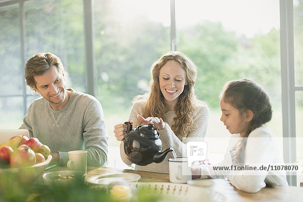 Mother pouring tea for daughter at dining table