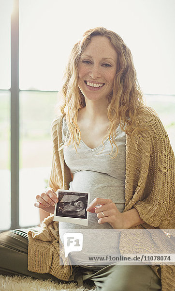 Portrait lächelnde schwangere Frau mit Ultraschall