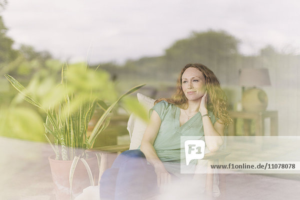 Pensive woman looking out living room window