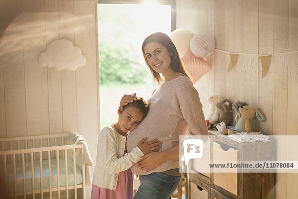 Portrait lächelnde schwangere Mutter und Tochter im Kinderzimmer