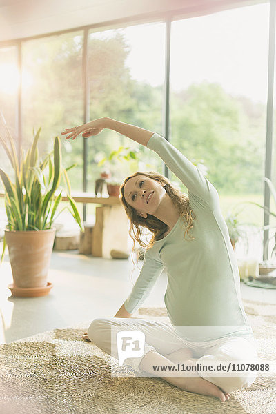 Schwangere Frau  die Yoga praktiziert  indem sie sich seitlich dehnt.