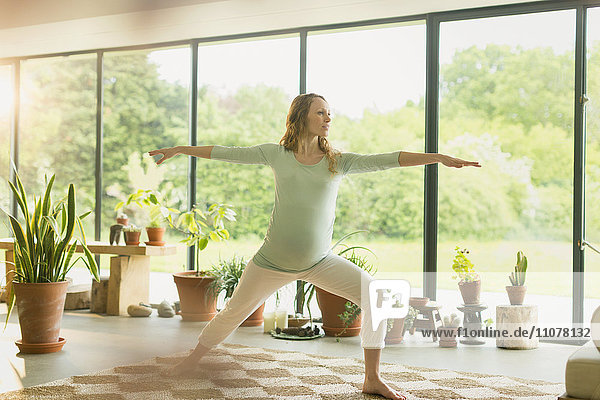 Schwangere Frau praktiziert Yoga-Kriegerin 2 Pose