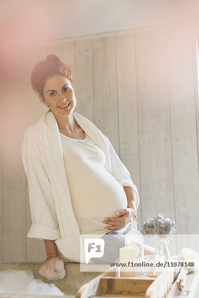 Portrait lächelnde schwangere Frau bei der Zubereitung des Schaumbades