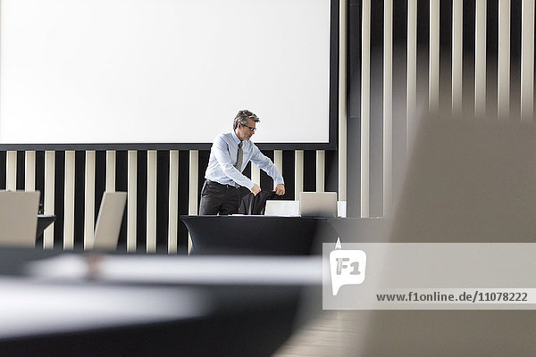 Businessman placing jacket on chair in conference room
