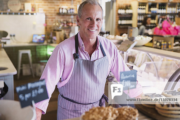 Portrait lächelnder Arbeiter hinter Desserts auf dem Markt