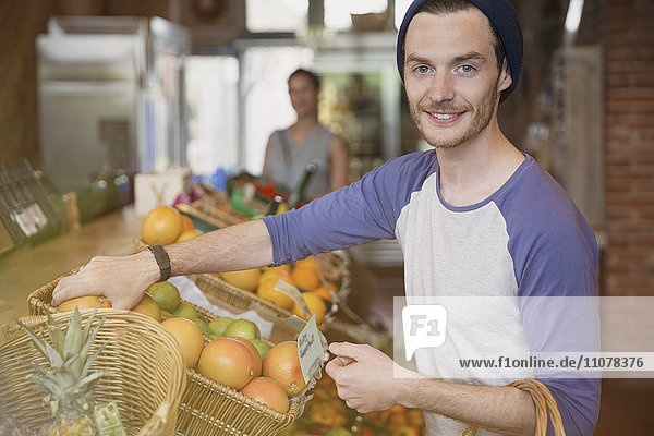 Portrait lächelnder Mann beim Orangeneinkauf auf dem Markt