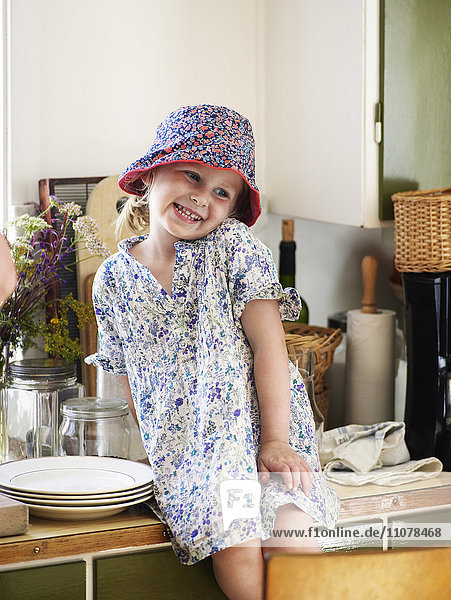Ein glückliches Mädchen sitzt auf einer Küchenarbeitsplatte.