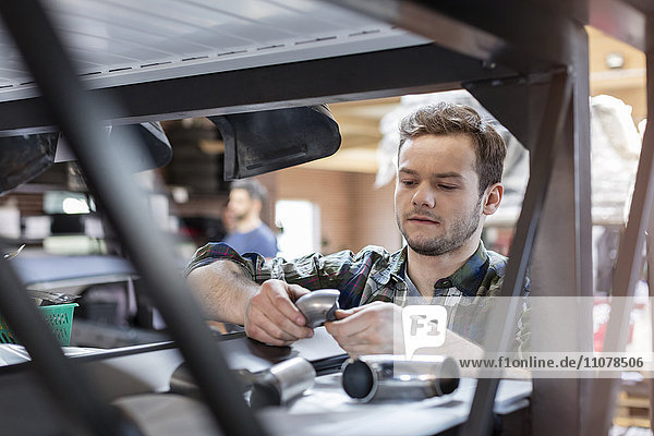 Focused mechanic examining car part in auto repair shop
