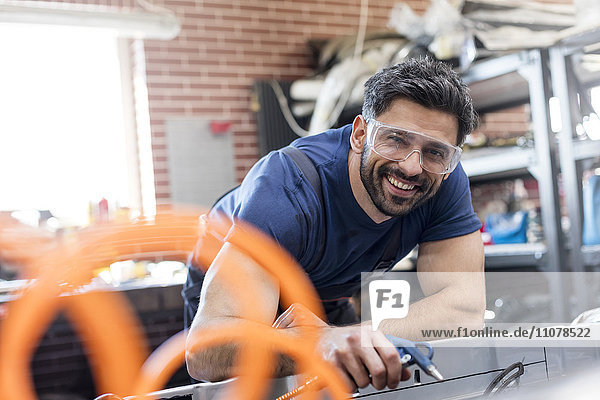 Porträt eines lächelnden Mechanikers in der Kfz-Werkstatt