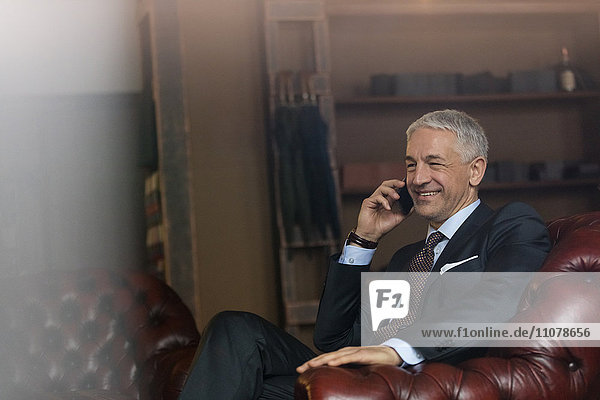 Lächelnder Geschäftsmann beim Telefonieren im Männermodegeschäft