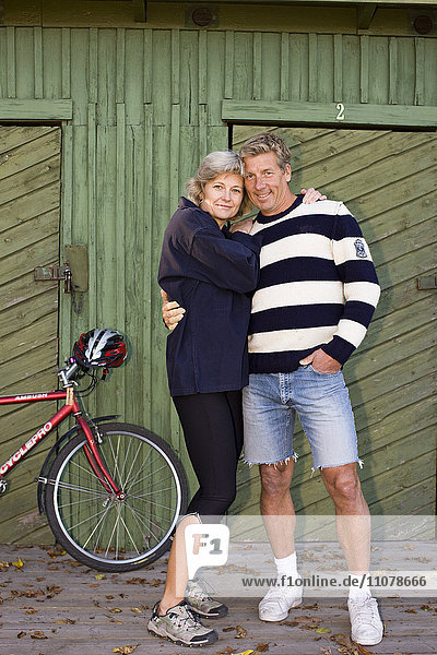 Ehepaar steht zusammen vor einem Holzhaus