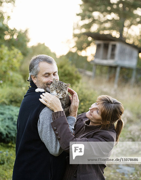 Älteres Paar umarmt Katze im Freien