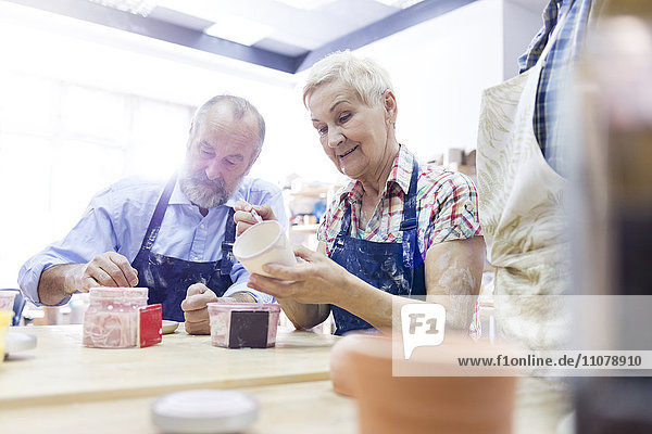 Seniorenpaar malt Keramik im Atelier