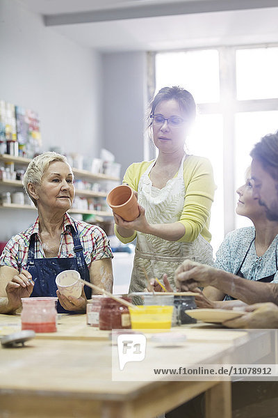 Lehrer  der reife Schüler beim Malen von Keramik im Atelier führt.