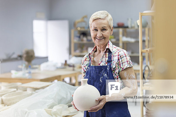 Portrait lächelnde Seniorin mit Keramikvase im Atelier