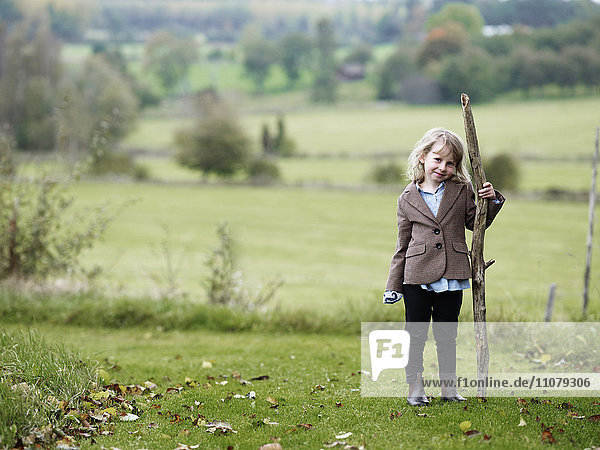Porträt eines Mädchens auf einem Feld  das einen Stock hält