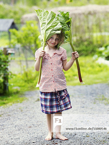 Portrait of girl holding rhubarb leaves