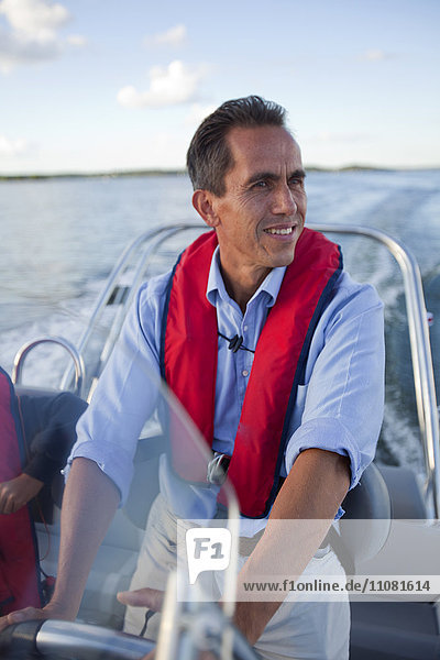 Lächelnder Mann am Steuer eines Motorboots