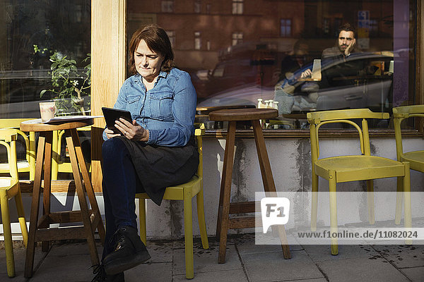 Die Besitzerin benutzt ein digitales Tablett  während sie im Café sitzt.