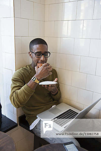 Junger Mann isst in einem Café Brötchen  Stockholm  Schweden