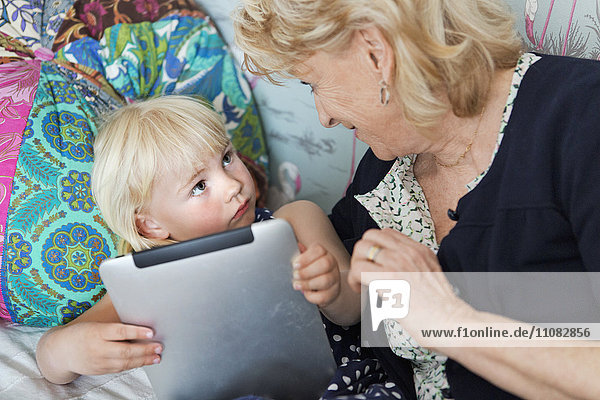 Großmutter mit Enkelkind bei der Nutzung eines digitalen Tablets