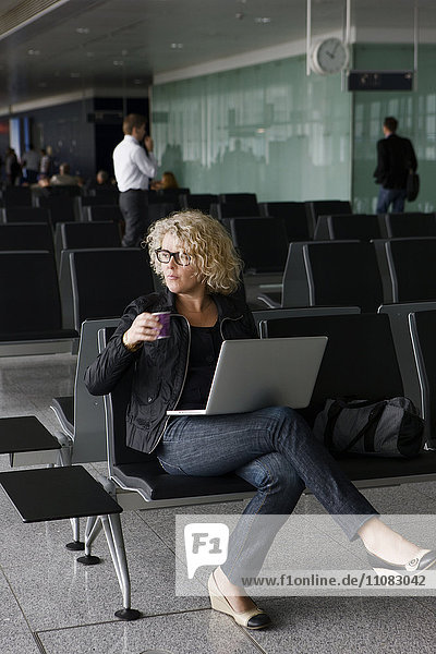 Mature woman with laptop at airport  Frankfurt  Germany