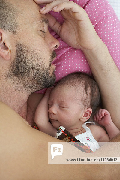 Father sleeping with newborn girl