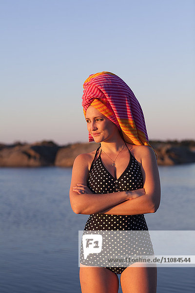 Junge Frau mit in ein Handtuch gewickelten Haaren am Meer