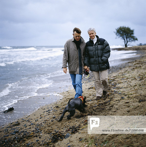 Ehepaar mittleren Alters geht am Strand spazieren  Schweden.