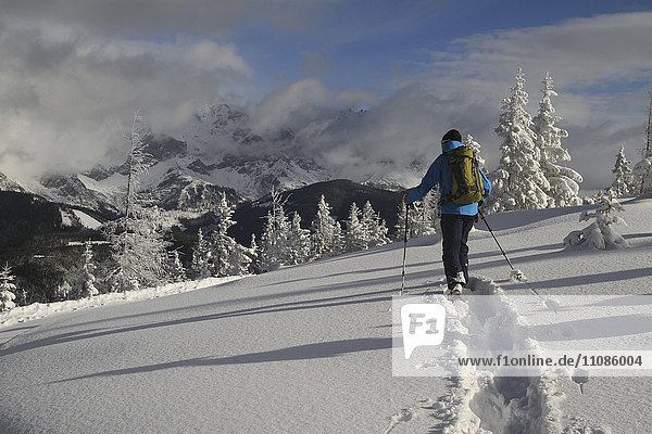 Mann in warmer Kleidung geht auf schneebedecktem Feld gegen die Berge