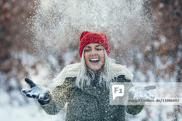 Glückliche junge Frau beim Spielen im Schnee