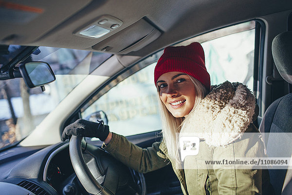Porträt einer fröhlichen Frau in warmer Kleidung beim Autofahren