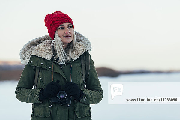 Nachdenkliche Frau mit Kamera genießt Wintersaison
