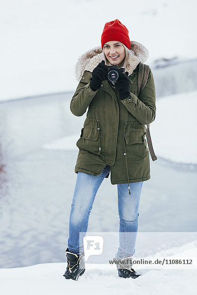 Schöne junge Frau  die im Winter durch die Kamera fotografiert.