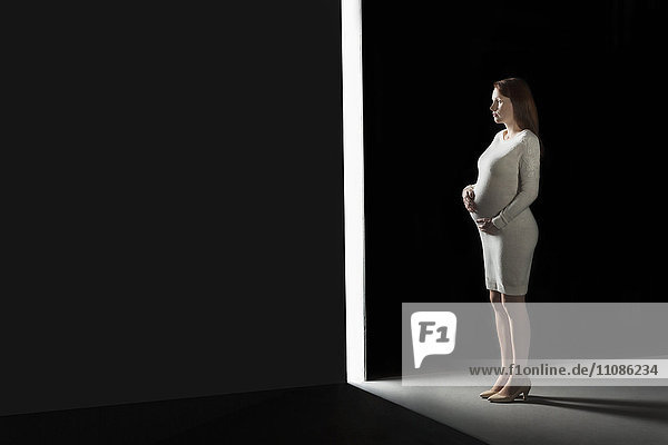 Durchgehende schwangere Frau mit Blick durch die Öffnung in der Wand