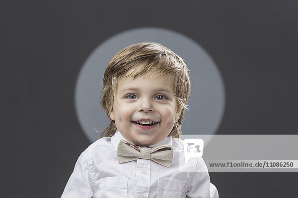 Portrait of cute boy with bowtie against gray background