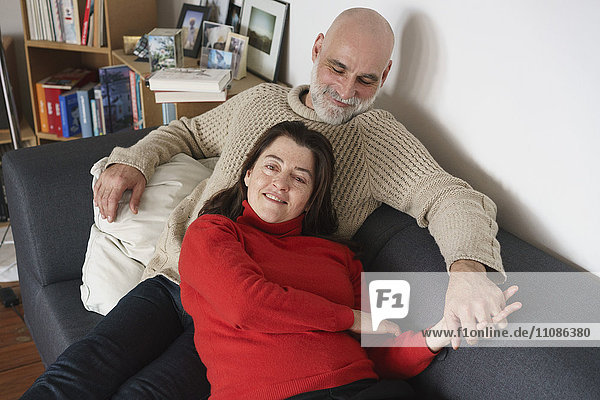 High angle view of mature couple relaxing on sofa at home